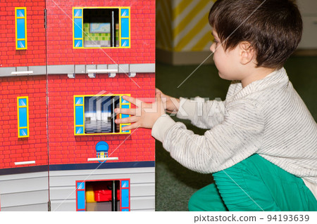 A 4-year-old boy plays in the playroom in the children's entertainment center with a toy big castle. A 4-year-old boy plays in the playroom in the children's entertainment center with a toy big castle. 94193639