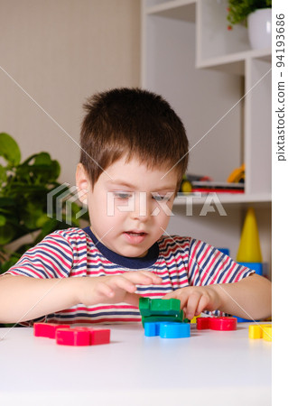 A boy of 4 years plays with multi-colored numbers, builds a tower 94193686