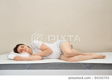 The woman sleeps on an orthopedic mattress and a pillow made of foam memory, a place for text 94193703
