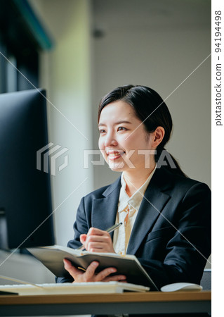 Young woman taking notes in her notebook in the office Young woman taking notes in her notebook in the office 94194498