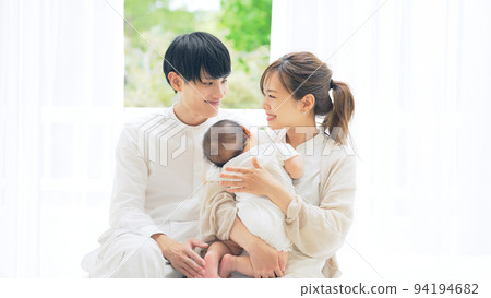Family image of a couple holding a baby relaxing in the room 94194682