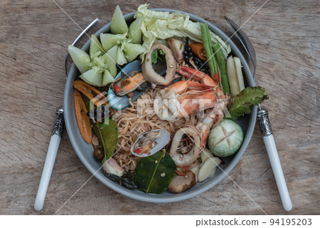 Spicy Stir Fried seafood Instant Noodles with herbs with various spices served with vegetables in ceramic plate. Spicy Stir Fried seafood Instant Noodles with herbs with various spices served with vegetables in ceramic plate. 94195203