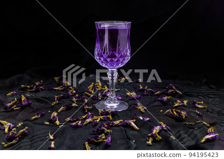 Flower violet color butterfly pea juice (Clitoria) in glass and dry butterfly pea flowers on dark background. 94195423