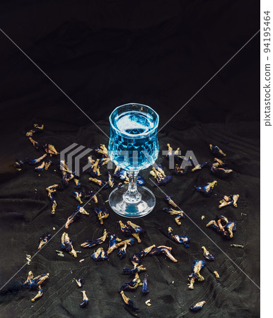 Glass of Cocktail butterfly pea or Flower anchan blue juice (Clitoria) and dry butterfly pea flowers on dark background. 94195464