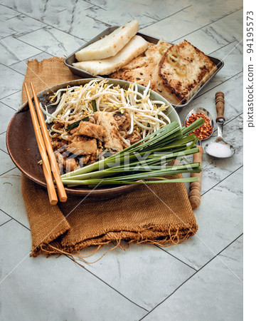 Stir fried soft turnip cake or Fried radish cake (chai tow kway) with bean sprout and chives in ceramic plate. Stir fried soft turnip cake or Fried radish cake (chai tow kway) with bean sprout and chives in ceramic plate. 94195573