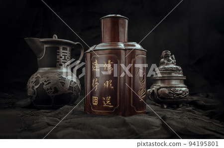 Chinese antique tea leaf iron storage jar (Characters chinese is Name of the tea), Chinese antique teapot (Characters chinese is Double Happiness) and Silver antique incense burner on dark background. 94195801
