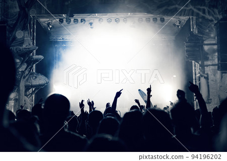 Crowd at a music concert, audience raising hands up, toned 94196202