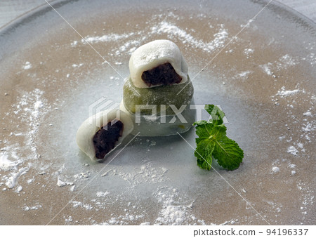 Red bean and Green tea daifuku serve with Mint leaves on Round ceramic tray. Red bean and Green tea daifuku serve with Mint leaves on Round ceramic tray. 94196337