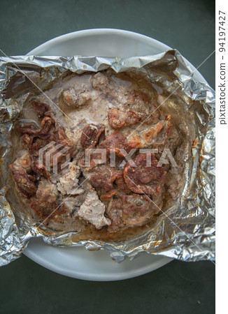 Baked sliced meat is baked in foil. Spices and herbs are wrapped in foil. Baked sliced meat is baked in foil. Spices and herbs are wrapped in foil. 94197427
