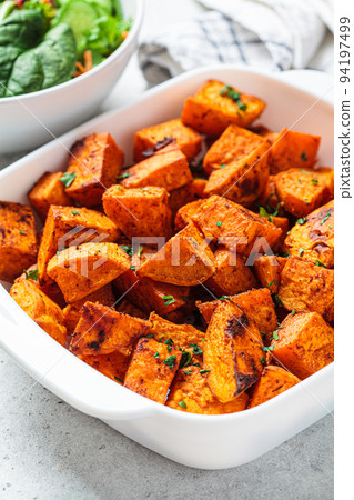 Spicy slices of baked sweet potato. Vegan food concept. Spicy slices of baked sweet potato. Vegan food concept. 94197499