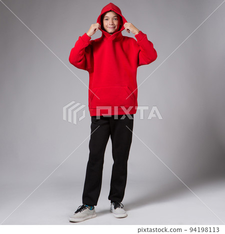 Teenage model in a red hoodie and black pants, studio shoot of clothes, the hood is thrown over her head Teenage model in a red hoodie and black pants, studio shoot of clothes, the hood is thrown over her head 94198113
