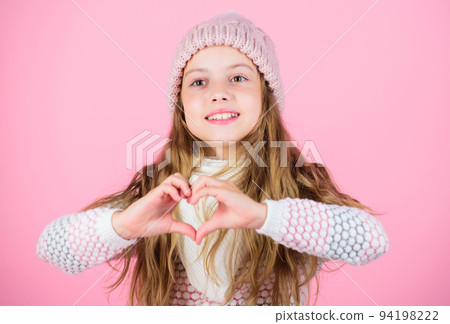 Girl wear knitted hat pink background. Look after scalp and hair this winter. Prevent winter hair damage. Winter hair care tips you should follow. Child long hair smiling show heart gesture 94198222