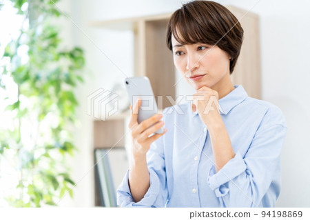 在客廳裡操作智能手機的中年女人 94198869