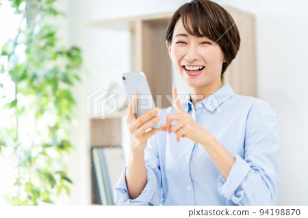 在客廳裡操作智能手機的中年女人 在客廳裡操作智能手機的中年女人 94198870