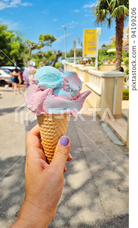 Gelato ice cream cone held up to the hot summer city 94199206