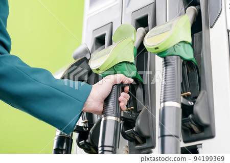 Refilling the car. At the gas station there are green pistols for refueling the car with gasoline. 94199369