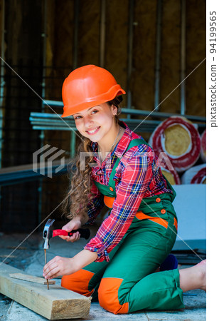 carpentry and woodwork concept. Portrait of a cute kid posing as a carpenter, with a hammer. working as woodworker. carpenter in protective hat work. girl working with wood in workshop carpentry and woodwork concept. Portrait of a cute kid posing as a carpenter, with a hammer. working as woodworker. carpenter in protective hat work. girl working with wood in workshop 94199565