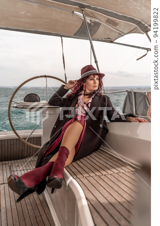 Attractive middle-aged woman at the helm of a yacht on a summer day. Luxury summer adventure, outdoor activities. Attractive middle-aged woman at the helm of a yacht on a summer day. Luxury summer adventure, outdoor activities. 94199822