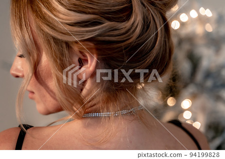 Portrait of a wealthy mature woman with evening makeup and hairstyle posing in a black dress against the backdrop of a Christmas room. Luxurious lifestyle. Cosmetology, plastic surgery, rejuvenation. Portrait of a wealthy mature woman with evening makeup and hairstyle posing in a black dress against the backdrop of a Christmas room. Luxurious lifestyle. Cosmetology, plastic surgery, rejuvenation. 94199828
