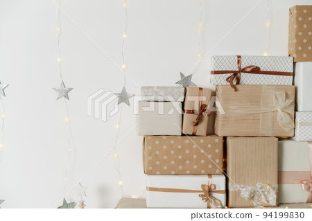 Pile of Christmas gifts in colorful wrapping with ribbons against a white wall with silver stars. Pile of Christmas gifts in colorful wrapping with ribbons against a white wall with silver stars. 94199830