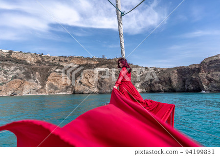 Attractive middle-aged woman in a red dress on a yacht on a summer day. Luxury summer adventure, outdoor activities. Attractive middle-aged woman in a red dress on a yacht on a summer day. Luxury summer adventure, outdoor activities. 94199831