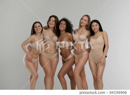Group of women with different body types in jeans and underwear taking selfie against light  94199906