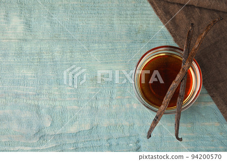 Aromatic homemade vanilla extract on light blue  wooden table, flat lay. Space for text 94200570