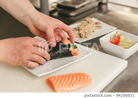 Close up of man japanese restaurant chef cooking sushi in the kitchen Close up of man japanese restaurant chef cooking sushi in the kitchen 94200851