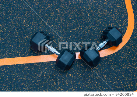 Rubber dumbbells dumbbell set sporting bodybuilding equipment on gym floor background Rubber dumbbells dumbbell set sporting bodybuilding equipment on gym floor background 94200854