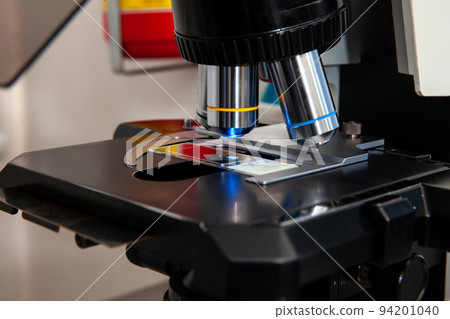 Closeup of a slide been analyzed under a fluorescence microscope in a genetics laboratory 94201040