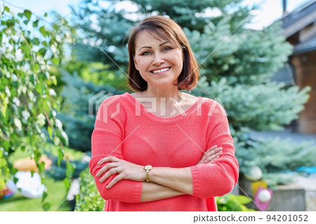 Portrait of smiling middle aged woman looking at camera outdoor 94201052