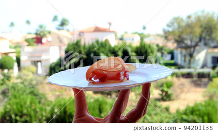 Plate with appetizing Spanish jamon against of Spanish landscape, palm trees, white houses, blue sky, tasty Jamon offer Plate with appetizing Spanish jamon against of Spanish landscape, palm trees, white houses, blue sky, tasty Jamon offer 94201138