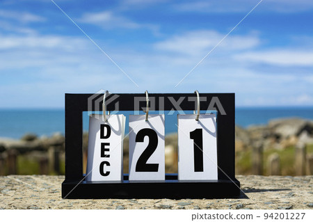 Dec 21 calendar date text on wooden frame with blurred background of ocean. 94201227