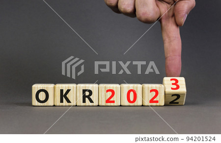 OKR, objectives and key results symbol. Businessman turns cubes with words OKR 2022 and OKR 2023 on beautiful grey background. Business OKR 2023 objectives and key results concept. Copy space. 94201524