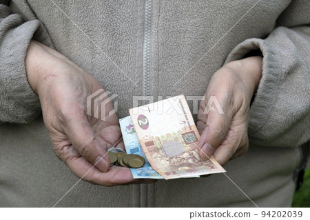A pensioner holds small Ukrainian hryvnia money, banknotes and coins in her hands 94202039