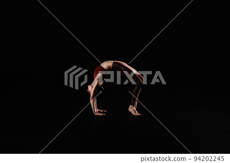 Young woman performing acrobatic element on stage indoors Young woman performing acrobatic element on stage indoors 94202245