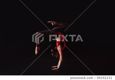 Young woman performing acrobatic element on stage indoors 94202252