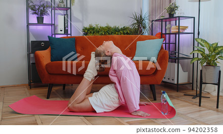 Young woman doing yoga stretching excersices on mat, workout, burning fat calories, training at home 94202358