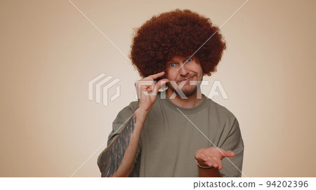 Man showing a little bit gesture with sceptic smile, showing minimum sign, measuring small size Man showing a little bit gesture with sceptic smile, showing minimum sign, measuring small size 94202396