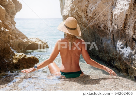 Beautiful blond woman in a straw hat on the beach of Corfu Beautiful blond woman in a straw hat on the beach of Corfu 94202406