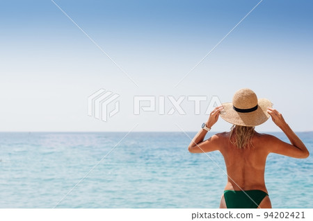 Beautiful blond woman in a straw hat on the beach of Corfu Beautiful blond woman in a straw hat on the beach of Corfu 94202421