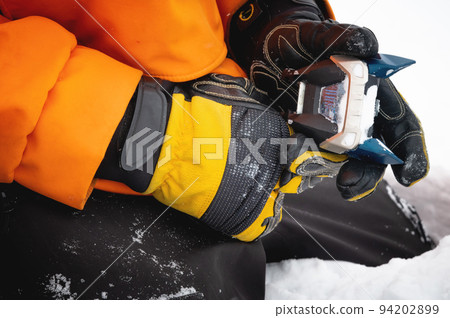 Setting up ski equipment, close-up of a hand for setting up and twisting ski boot bindings on a mountain in the snow 94202899