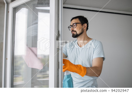 Bearded caucasian man in eyeglasses, sitting on stepladder holding sponge for washing windows Bearded caucasian man in eyeglasses, sitting on stepladder holding sponge for washing windows 94202947