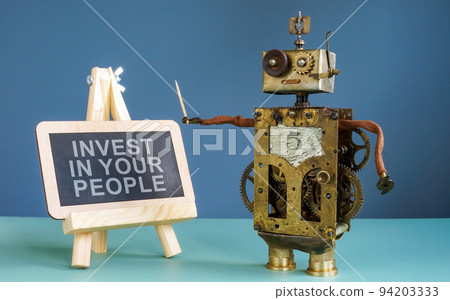 Robot near blackboard with sign invest in your people. Robot near blackboard with sign invest in your people. 94203333
