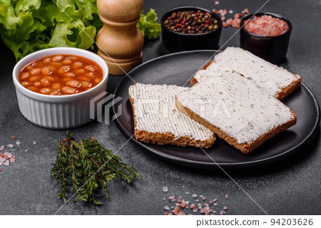 Traditional English breakfast with eggs, toast, sausages, beans, spices and herbs on a grey ceramic plate 94203626