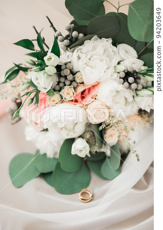 Beautiful toned picture with wedding rings against the background of a bouquet of flowers Beautiful toned picture with wedding rings against the background of a bouquet of flowers 94203649