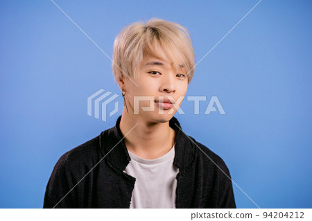Portrait of stylish korean man looking to camera. Asian guy with dyed blonde hairstyle in studio on 94204212