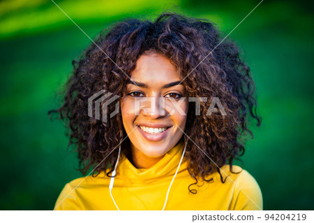 Portrait of african american girl in white earphones. Young woman with curly hairstyle in yellow Portrait of african american girl in white earphones. Young woman with curly hairstyle in yellow 94204219