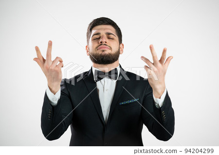 Young man making delicious, perfect gesture. Guy with beard in tuxedo admires taste of italian food 94204299