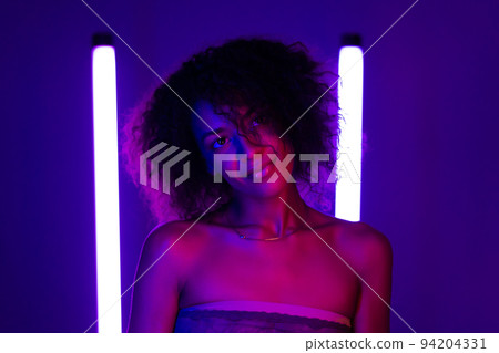 Multi ethnic woman with curly african hair on violet background in purple neon light. Sexy charming 94204331
